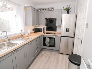 A kitchen with gray cabinets a stainless steel sink microwave oven and refrigerator at Stones Throw in Amble