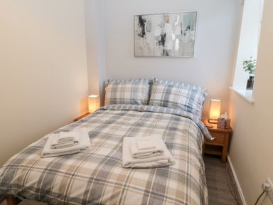 A bedroom with a double bed and two bedside tables with lamps at Stone's Throw in Amble