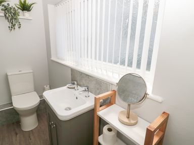 A bathroom with a toilet sink and mirror on a shelf at Stones Throw in Amble