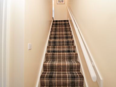 A staircase with plaid carpet and beige walls at Stones Throw in Amble