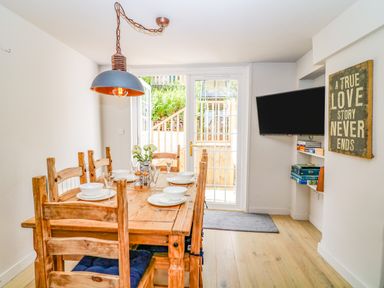 A dining room with a wooden table set for six and a wall-mounted television at Hillside in Crafthole