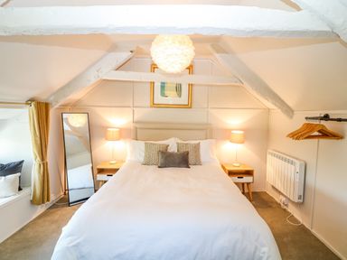 A bedroom with a bed and two bedside tables with lamps and a wall-mounted coat rack at Hillside in Crafthole