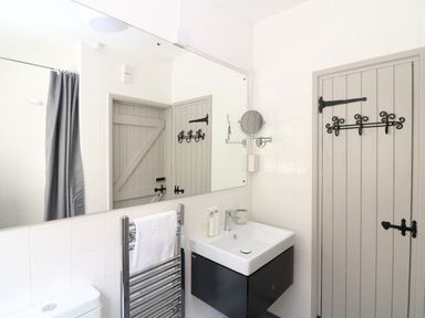 A bathroom with a sink unit towel rack toilet door and mirror at Hillside in Crafthole