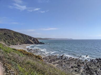A rocky coastline with a sandy beach and cliffs at Hillside in Crafthole