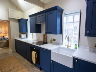 A kitchen with blue cabinets white countertops a sink stove oven microwave and a window at The Tower in Kirklinton near Longtown