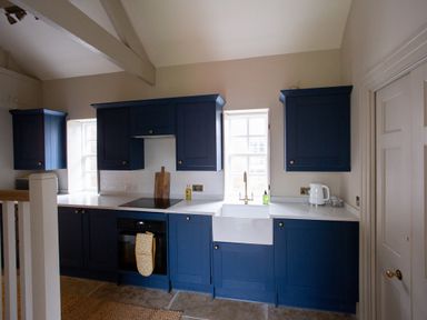 A kitchen with blue cabinets a white countertop a sink and an oven at The Tower Kirklinton near Longtown