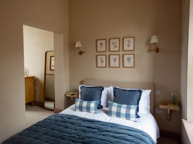 A bedroom with a bed with blue pillows and blanket and framed pictures on the wall at The Tower in Kirklinton near Longtown