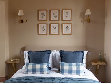 A bedroom with a bed with blue and white pillows and framed botanical prints on the wall at The Tower in Kirklinton near Longtown