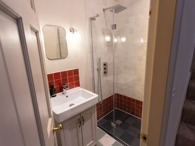 A small bathroom with a sink, mirror, and walk-in shower at The Tower in Kirklinton near Longtown