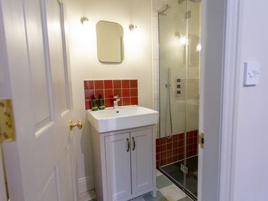 A bathroom with a sink and cabinet a mirror and a glass door shower at The Tower in Kirklinton near Longtown