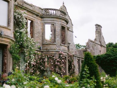 An old stone building with arched windows and climbing flowering plants at The Tower in Kirklinton near Longtown