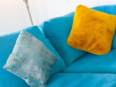A blue sofa with a patterned blue cushion and a yellow cushion in a living room at Moonbeams in Carbis Bay