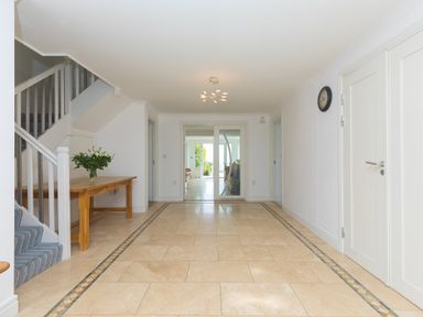 An entrance hallway with tiled floor a wooden table with flowers on the left and stairs leading up on the left at Moonbeams in Carbis Bay