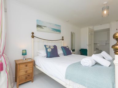 A bedroom with a double bed and nightstand with lamp at Moonbeams in Carbis Bay