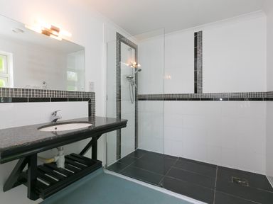 A bathroom with a granite countertop sink and a walk-in shower with glass partition at Moonbeams in Carbis Bay