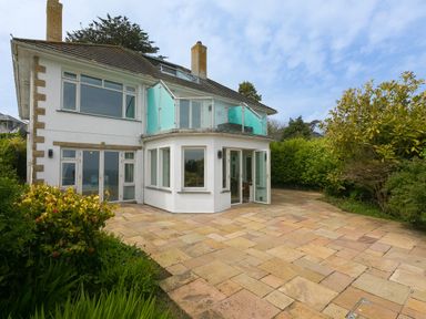 An exterior view of a two-story house with a tiled patio and glass balcony at Moonbeams in Carbis Bay