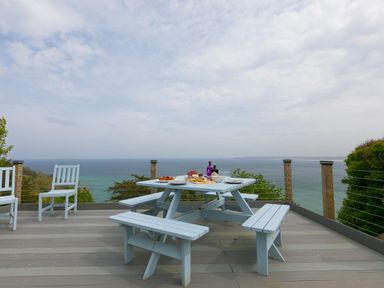 A patio with light blue picnic table and chairs overlooking the sea with food and drink on the table at Moonbeams in Carbis Bay