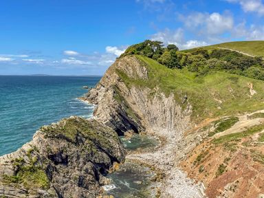 A rocky coastline with cliffs and vegetation beside the sea at West Lulworth Apartment in West Lulworth