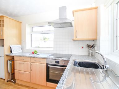 A kitchen with wooden cabinets a stainless steel oven and sink at West Lulworth Apartment in West Lulworth