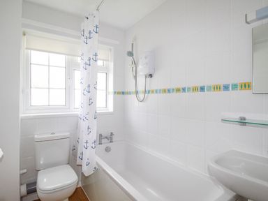 A bathroom with a bathtub shower toilet and sink at West Lulworth Apartment in West Lulworth