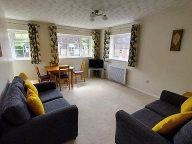 A living room with sofas, a table and a television at West Lulworth Apartment in West Lulworth