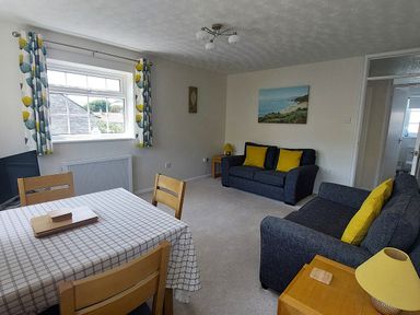 A living room with a table and chairs at West Lulworth Apartment in West Lulworth