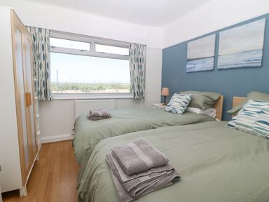 A bedroom with two single beds green bedding pillows wardrobe and a window with curtains at Awelfryn in Elim near Llanddeusant