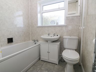 A bathroom with a bathtub sink toilet and a frosted window at Awelfryn in Elim near Llanddeusant