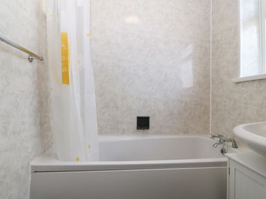 A bathroom with a bathtub shower curtain and sink at Awelfryn in Elim near Llanddeusant