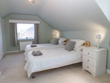 A bedroom with two single beds bedside tables and a window at Awelfryn in Elim near Llanddeusant