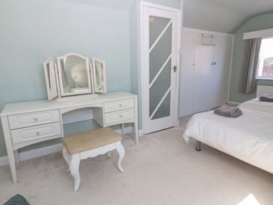 A bedroom with a white dressing table and stool and two beds with folded towels at Awelfryn in Elim near Llanddeusant