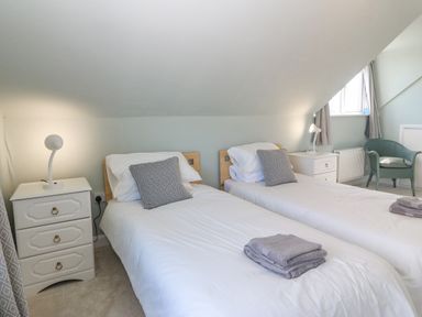A bedroom with two single beds bedside tables lamps and a chair at Awelfryn in Elim near Llanddeusant