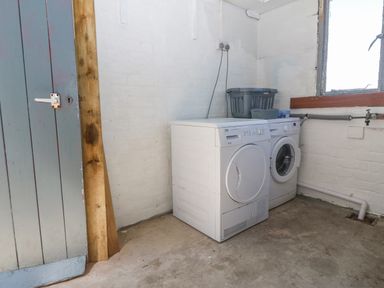 A laundry room with a washing machine and a dryer next to a window at Awelfryn in Elim near Llanddeusant