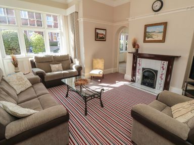 A living room with sofas glass coffee table striped carpet and fireplace at Lonsdale Villa in Scarborough