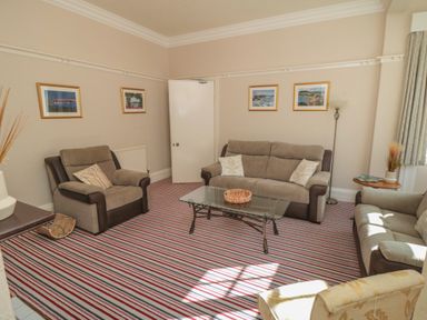 A sitting room with three sofas a glass coffee table and framed pictures on the walls at Lonsdale Villa Scarborough