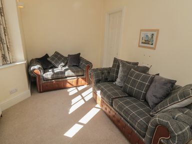 A living room with two checkered sofas with cushions and a framed picture on the wall at Lonsdale Villa in Scarborough