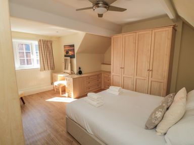 A bedroom with a bed towels and pillows a wardrobe and a desk with a chair at Lonsdale Villa in Scarborough