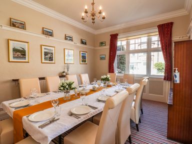 A dining room with a long table set with plates glasses and cutlery and chairs around it at Lonsdale Villa in Scarborough