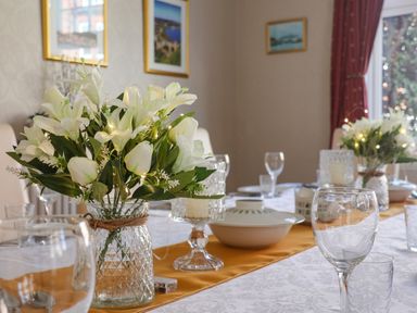 A dining table set with glassware a bowl and two vases of white flowers at Lonsdale Villa in Scarborough