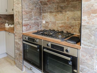 A kitchen with two built in ovens and a gas stovetop with tiled backsplash at Lonsdale Villa in Scarborough
