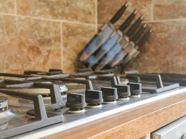 A close up of a gas stove with control knobs and a knife block with knives in a kitchen at Lonsdale Villa in Scarborough