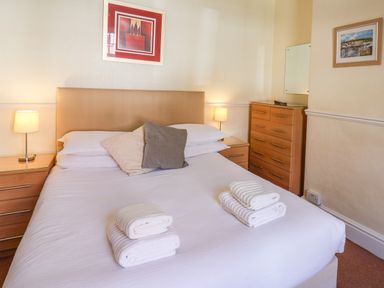 A bedroom with a double bed two bedside tables with lamps a chest of drawers and framed pictures on the walls at Lonsdale Villa in Scarborough