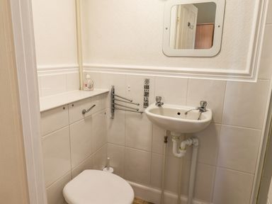 A small bathroom with a toilet sink mirror and soap dispenser at Lonsdale Villa Scarborough