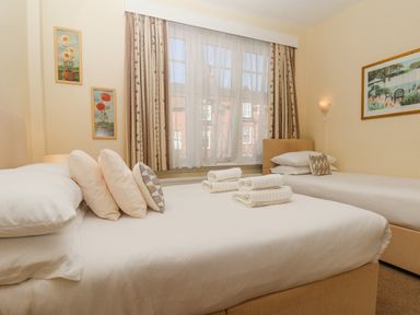 A bedroom with two beds pillows folded towels and framed pictures on the walls at Lonsdale Villa in Scarborough