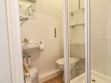 A small bathroom with a sink toilet shower and glass shelves at Lonsdale Villa in Scarborough