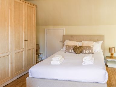 A bedroom with a double bed with several pillows and folded towels a wardrobe and bedside tables with lamps at Lonsdale Villa in Scarborough