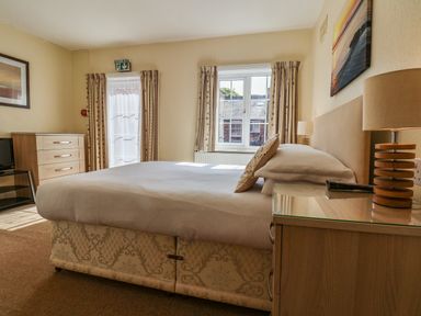 A bedroom with a double bed bedside tables lamps curtains and a chest of drawers at Lonsdale Villa in Scarborough