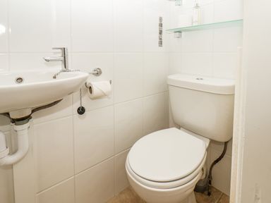 A small bathroom with a toilet a sink and a toilet paper holder at Lonsdale Villa in Scarborough