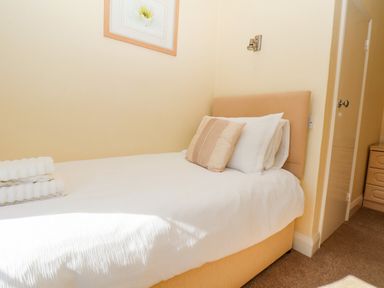 A bedroom with a single bed with white bedding pillows and folded towels on the bed at Lonsdale Villa Scarborough