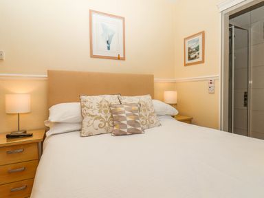 A bedroom with a double bed two bedside tables lamps and framed pictures at Lonsdale Villa in Scarborough